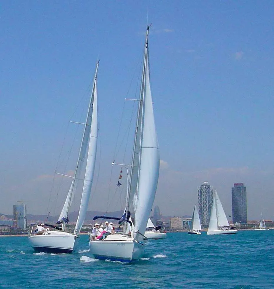 Sailboats sailing upwind with the Barcelona skyline behind
